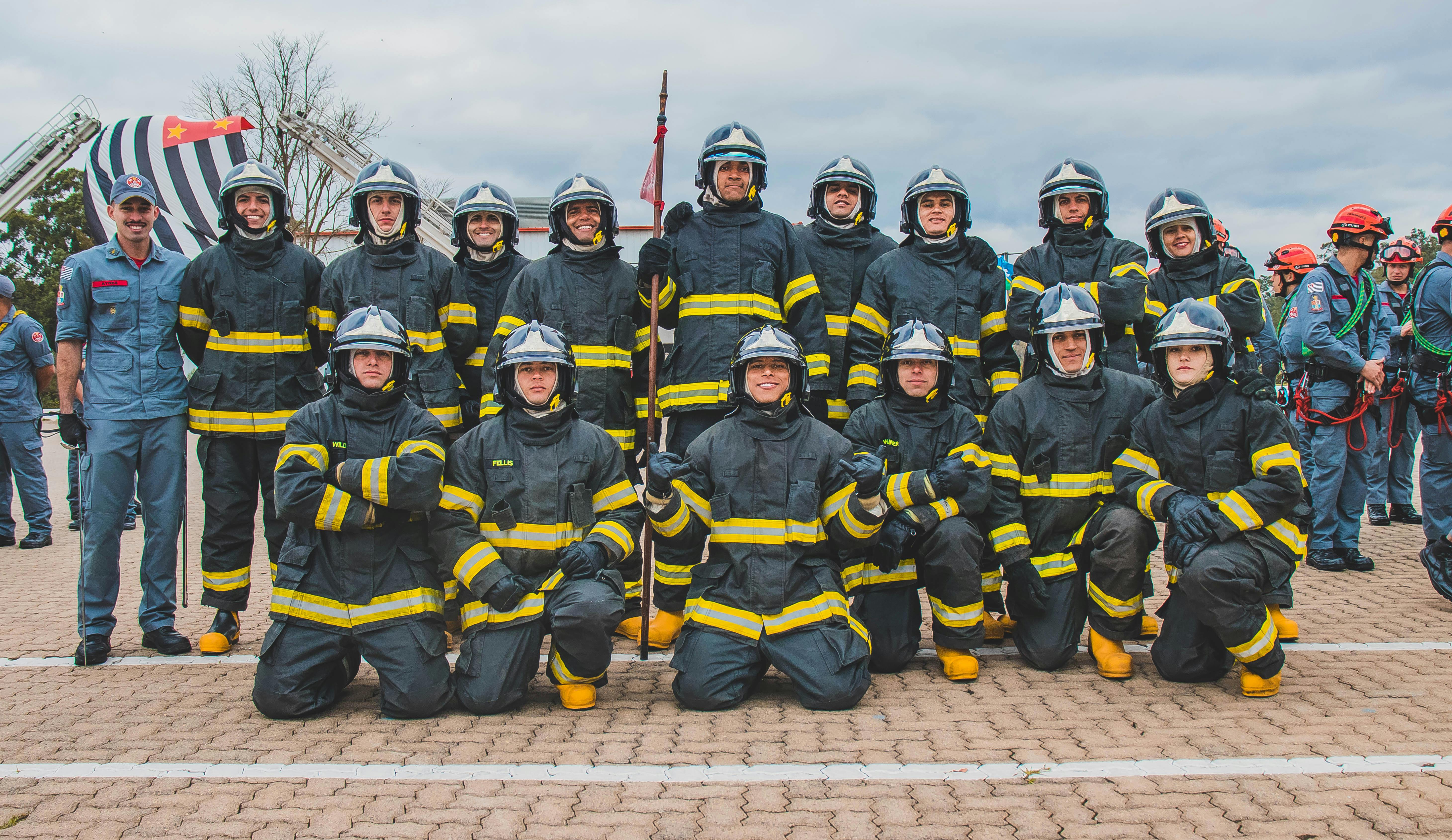 A diverse group of firefighters smiling and posing together outdoors.